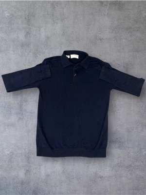 Mörkblå pikétröja från Selected Homme - Snygg mörkblå pikétröja från Selected Homme med klassisk krage och två knappar framtill. Tröjan har långa ärmar och är tillverkad i mjukt material som känns bekvämt mot huden. Perfekt för en stilren och avslappnad look.