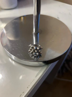 Silvrig ring med nitar - Cool och chunky ring i silverfärgad metall med flera rader av små nitar runt hela ringen. Ringen har en bred design och ger en edgy vibe till din stil. Perfekt för dig som gillar statement-smycken och vill sticka ut lite extra. Ifrån Edblad 