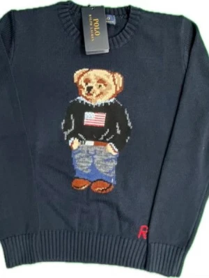 Polo Bear - Mörkblå stickad tröja från Polo Ralph Lauren med ikoniskt Polo Bear-motiv på bröstet. Björnen har på sig jeans, svart tröja med amerikansk flagga och bruna skor. Tröjan har ribbade muddar och rund hals. Perfekt statement-plagg för dig som gillar klassisk streetstyle.