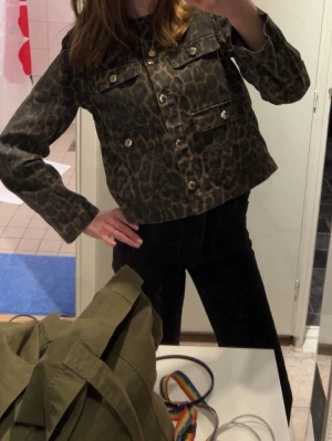 Leopardmönstrad jeansjacka - Säljer en trendig jeansjacka med leopardmönster och silvriga knappar. Jackan har två bröstfickor med lock och två fickor nedtill. Kortare modell som ger en cool och edgy look. Perfekt för dig som vill sticka ut lite extra. Jackan är i storlek Xs och jag har använt den som en tröja eftersom att den är ganska tunn. Köpt på hm och är i nyskick! Inga defekter. 🩷