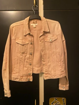 Två jeansjackor i pastell och ljusblå - Säljer två snygga jeansjackor, en i ljus pastellrosa och en i klassisk ljusblå denim. Båda har bröstfickor med lock och knapp, samt sidofickor. Perfekt oversized fit och tidlös design med metallknappar framtill.