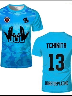 Blå sporttröja med tryck - Snygg blå sporttröja med kamouflagemönster och svart tryck framtill. På bröstet finns loggor och ett grafiskt handmotiv med texten 'JUJU'. Baksidan har namnet 'TCHIKITA', siffran 13 och texten 'DORETDEPLATINE'. Perfekt för träning eller match.