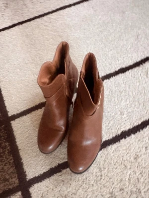Bruna stövletter med gulddetalj - Snygga bruna stövletter vet inte vad för märke helt nya rena använda några gånger men inga tecken på smuts eller användning de är fett fina och sköna 