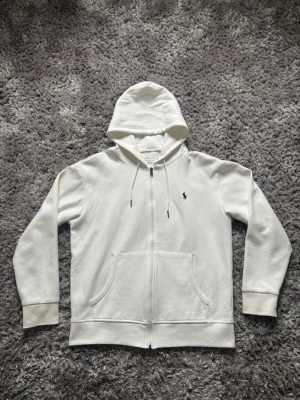 Ralph Lauren zip-hoodie - Säljer min ralph lauren hoodie då den inte används längre. Den är i bra skick, inga fläckar eller slitage på den bortsett från trycket i nacken som börjat släppa lite. Storlek medium men skulle säga att den sitter som en large