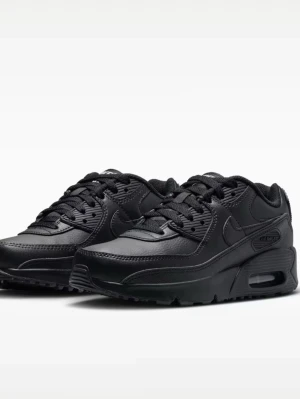 Nike Air Max 90 helsvarta sneakers - Snygga helsvarta Nike Air Max 90 sneakers med klassisk siluett. Skorna har ovandel i läder och mesh, synlig Air-enhet i sulan och ikoniska swoosh-loggan på sidan. Perfekta för dig som gillar en clean och tidlös look.