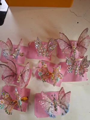 Glittriga fjärilshårspännen rosa - Säljer flera hårspännen formade som fjärilar i olika nyanser av rosa och pastell. Spännena är dekorerade med glitter, pärlor och små blommor för en extra söt look. Perfekta för att piffa upp frisyren med en lekfull och trendig touch.  35sek/st 3 for 85sek