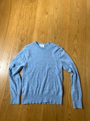 Merinoull tröja från Sandö - Ljusblå stickad tröja från SANDÖ med rund halsringning och långa ärmar. Tröjan har ribbade muddar vid ärmslut och nederkant, och är tillverkad i ett mjukt, tunt material som passar perfekt för lager på lager. Skulle säga att den sitter som XS!