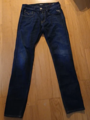 Mörkblå jeans från Replay - Snygga mörkblå jeans från Replay med klassisk femficksmodell och raka ben. Jeansen har kontrastsömmar och en diskret logga på bakfickan. Tillverkade i ett slitstarkt denimtyg som ger en cool look. W30 L34 helt nya utan prislapp 