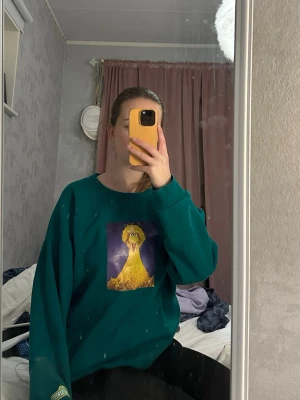 Grön sweatshirt med Big Bird-tryck - Cool grön sweatshirt från H&M med ett stort tryck av Big Bird från Sesame Street på bröstet. Tröjan har rund halsringning, långa ärmar och mjukt material som känns skönt mot huden. Perfekt för dig som gillar färg och vill sticka ut lite extra.