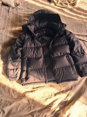 Svart Ralph lauren vårvinter jacka - Jag säljer en svart vår-vinterjacka från Ralph lauren. Storlek 18-20, men passar som en Si vuxen storlek eller för en pojke 14-16 runt 170cm lång. Prislapp finns med är i nästan samma skick som jag köpte den i, Orginalpriset ligger på cirka 3500kr. Priset kan diskuteras  OBS! Jackan har en mindre defekt på ena ärmen, finns på sista bilden. Bortsett från detta lilla hål är jackan i nyskick