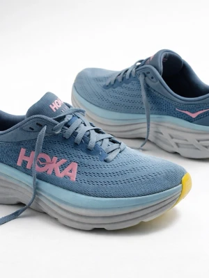 Blå löparskor från Hoka - Snygga blå löparskor från Hoka med rosa logga på sidan och detaljer i gult på tån. Ovandelen är i ventilerande mesh och sulan är tjock och dämpande i grått och ljusblått. Perfekta för dig som vill ha komfort och stil på löprundan.