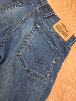 Blå jeans från Replay Anbass - Säljer ett par klassiska blå jeans från Replay, modell Anbass. 5 fickor, en massa replayloggor, riktigt fin färg och fin passform. Dessutom är det ett väldigt töjbart tyg, så den passar långt my ket mer än 30. Jag tänker runt 250kr som pris, men som vanligt går det att snacka ned priset lite. Hade gött