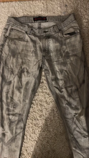 Grå washed jeans med raka ben - Säljer ett par grå jeans med washed effekt och raka ben. Jeansen har klassisk femficksmodell, bälteshällor och knappgylf. Snyggt slitna detaljer för en avslappnad look. Perfekta till sneakers eller boots.