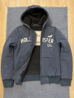 Pälsfodrad Vintage Hollister Kofta - Säljer denna tvär feta Hollister koftan med pälsfodring, perfekt till kallare dagar! | Storlek L | Längd ≈ 74, Bredd armhåla-armhåla ≈ 58| Hör av vid funderingar, pris kan diskuteras!!