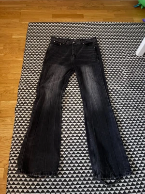Svarta bootcut jeans från balenciaga - Säljer ett par svarta bootcut jeans med lätt slitna detaljer och markerade sömmar längs benen. Jeansen har klassisk femficksmodell och är tillverkade i denim med stretch. Perfekta för dig som gillar en retro och avslappnad look.
