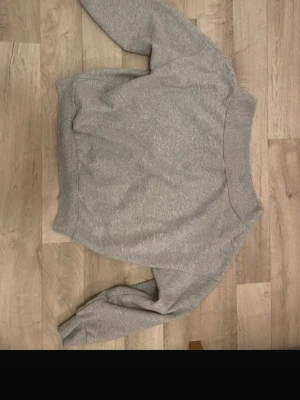 Grå sweatshirt of shoulder - En basic grå ofshoudler sweatshirt i mjukt material med rund hals och ribbade muddar vid ärmslut och nederkant. Perfekt för en avslappnad och enkel stil. Passar till det mesta och är lätt att matcha med andra plagg.