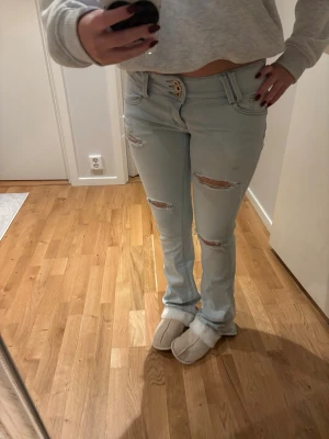 Low waist bootcut jeans - Säljer dessa ljusblå lågmidjade jeans med hål, 