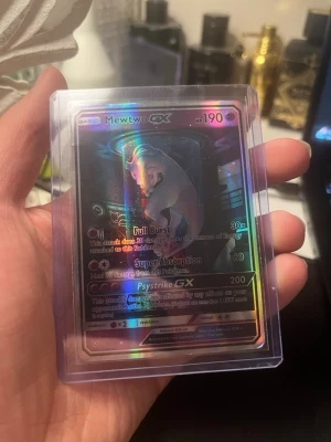 Pokémonkort Mewtwo GX holografisk - Säljer ett Pokémonkort med Mewtwo GX, holografisk design. Kortet har 190 HP och attacker som Full Burst, Super Absorption och Psystrike GX. Kortet är i en genomskinlig plastficka och har en färgstark, glansig yta.