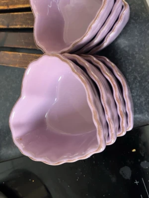 7 stycken skålar - Säljer ett set med lila hjärtformade skålar i keramik. Skålarna har en vågig kant och en blank finish, perfekta för snacks, dessert eller småplock. Färgen är en mjuk pastellila som ger ett gulligt intryck på bordet.