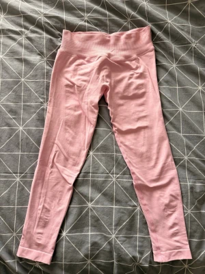 Ljusrosa seamless leggings - Säljer ett par ljusrosa seamless leggings med hög midja och stretchigt material. Perfekta för träning eller chill. Mjuka och följsamma med ribbad linning för extra komfort. Aldrig använt, nypris 699kr.