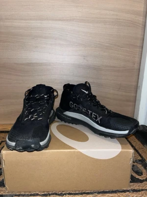 Nike trail Gore-Tex storlek 44 - Säljer ett par svarta Nike kängor med Gore-Tex material som gör dem vattentäta och perfekta för tuffare väder. Skorna har grov sula för bra grepp, reflekterande detaljer och snörning. Snygg sportig design med vita detaljer och logga på sidan.