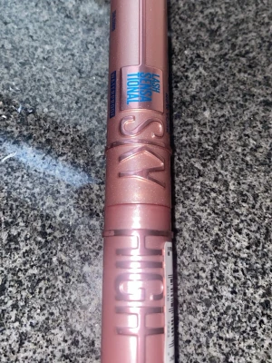 Maybelline Lash Sensational Sky High Mascara - Säljer en Maybelline Lash Sensational Sky High Mascara i en snygg roséguldig tub med glittrig finish. Tuben är cylinderformad och har blå text och detaljer. Perfekt för att ge fransarna längd och volym. Vattenfast formula.