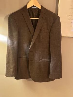 Brun kavaj från sand Copenhagen  - Stilren brun kavaj från Massimo Tessuto med klassisk passform. Kavajen har två fickor fram, en bröstficka och snyggt mönstrat innerfoder. Perfekt för dig som vill ha en tidlös och elegant look.