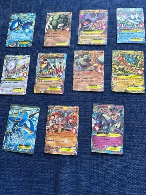 Samling Pokémongokort EX och Mega - Säljer en samling med 11 Pokémonkort, bland annat EX och Mega-versioner som Kyogre, Groudon, Lucario och Golem. Korten har färgstarka illustrationer och holografiska effekter. Perfekt för dig som vill utöka din samling med unika och coola kort. Alla kort är på engelska och har klassisk rektangulär form.