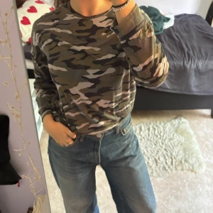 Kamouflagetröja - Kamouflagemönstrad långärmad tröja från Gina tricot i storlek M. Lätt nopprig och har ett litet, näst intill osynligt hål på nedre framsida. Material: 100% viskos :)