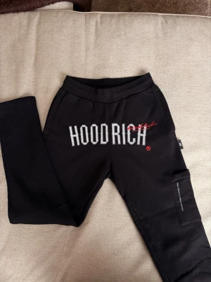 Hoodrich byxor svarta - Jag säljer svarta Hoodrich mjukisbyxor med hoodrich märket framtill, raka ben och en sidfick. Köpt från JD Sport och är aldrig använda.