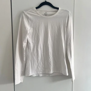 Vit långärmad topp - Klassisk vit långärmad topp i mjuk bomull med rund halsringning. Enkel och stilren design som passar till det mesta. Perfekt basplagg för garderoben.