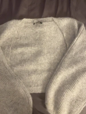 Ljusgrå stickad cardigan  - Mysig ljusgrå stickad cardigan med öppen front och ribbstickad struktur. Perfekt för lager-på-lager och enkel att matcha med olika outfits. Långa ärmar och mjukt material som känns skönt mot huden.