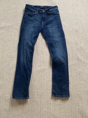 Blue denim regular jeans från Jack & Jones - Snygga mörkblå slim fit jeans från Jack & Jones med klassisk femficksdesign och raka ben. Men har går sönder där bak bild 5