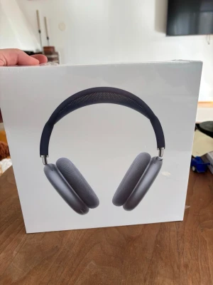 Apple AirPods Max hörlurar grå - Snygga int all-ear hörlurar från Apple, modell AirPods Max i en stilren grå färg. De har en mjuk transferad bygel och öronkuddar i mesh-tyg för extra komfort. Designen är modern och premium med aluminium och rostfritt stål.