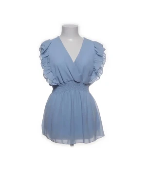 Ljusblå volangblus med v-ringning - Supersöt ljusblå blus med v-ringad hals och volangdetaljer längs ärmarna. Smockad midja ger en snygg siluett och det tunna, luftiga tyget gör toppen perfekt för varma dagar. Passar perfekt till jeans eller kjol för en fräsch look.