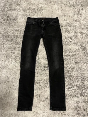 Svarta straigt jeans från nudie  - Säljer ett par svarta straigt jeans från Nudie Jeans med klassisk femficksdesign och knappgylf. Jeansen har en lätt tvättad look och raka ben. Perfekta för dig som gillar en enkel och stilren stil. W30 L32. PRIS KAN DISKUTERAS‼️