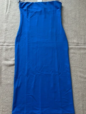 Mng axelbandslös långklänning från Mango  - Snygg blå axelbandslös långklänning från Mango med figurnära passform. Klänningen har en enkel och stilren design utan mönster och är perfekt för dig som gillar minimalistisk stil. Tillverkad i ett mjukt och stretchigt material som sitter bekvämt. Nypris 1100kr passar utmärkt på en M också 