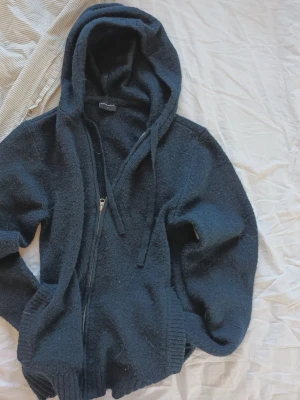 Mörkblå hoodie med dragkedja - Mysig mörkblå hoodie från Firefly med dragkedja framtill, stor huva och dragsko. Tillverkad i ett mjukt, stickat material som känns riktigt skönt. Ribbstickade muddar vid ärmslut och nederkant samt fickor på sidorna. Perfekt för en avslappnad look. (Ignorera hundhåret skulle såklart ta bort det innan jag skickar)