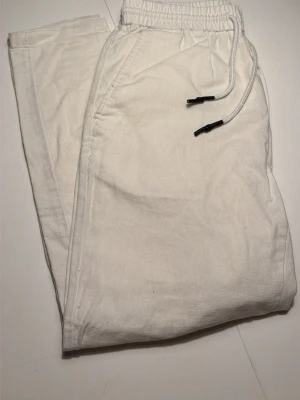 Vita linnebyxor från Only and Sons - Snygga vita linnebyxor från Only and Sons med avslappnad couch fit, elastisk midja. Byxorna har sidofickor och är gjorda i ett luftigt linn bowl material som känns riktigt fräscht. Perfekt för chill dagar när du vill ha en clean och enkel stil droppad.