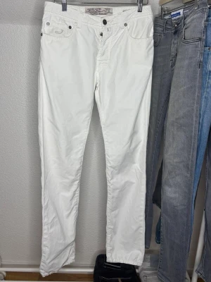 Vita raka jeans från Jacob Cohen - Säljer ett par vita jeans från Jacob Cohen med rak passform och klassisk femficksdesign. Jeansen har knappgylf och diskreta sömmar. Tillverkade i mjukt bomullstyg som ger en skön känsla och stilren look. Det är W33 men sitter som W32