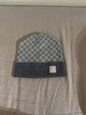 Grå mössa med rutmönster - Snygg grå mössa med klassiskt rutmönster och vikt kant.