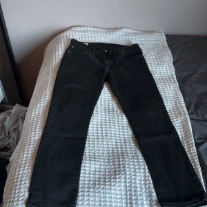 Svarta raka jeans från Levi's - Säljer ett par svarta jeans från Levi's med klassisk femficksdesign och raka ben. Jeansen har normal midja och dragkedjegylf. Perfekta för en stilren och avslappnad look. Liten i storleken 