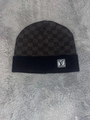  svart grå  rutmönstrad mössa - Säljer en svart och mörkgrå rutmönstrad mössa från Zara . Mössan har en vikt kant med Zara -logga framtill och är tillverkad i ett mjukt stickat material. Perfekt för dig som vill ha en stilren accessoar med lyxig känsla.