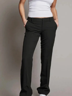 Svarta raka kostymbyxor - Snygga svarta kostymbyxor med rak passform och pressveck. Byxorna har låg midja, hällor för skärp och diskreta sidofickor. Perfekta för en clean och stilren look. Jag har sytt ner dom så dom skulle passa på mig som är ca 170