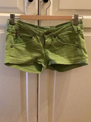 Gröna shorts från Killah med dragkedjor - Säljer ett par coola gröna shorts från Killah med snygga detaljer som dragkedjor på bakfickorna och broderad logga på framsidan. Shortsens passform är lågmidjad och de har klassiska fickor både fram och bak. Perfekta för sommarens alla äventyr! Y2k, har ej använt de så de är i väldigt bra skick. Kolla gärna igenom alla bilder! 🫰🏼