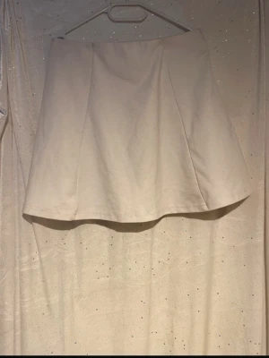 Vit kortkjol i bomull - Snygg vit kortkjol i bomull med enkel och stilren design. Kjolen har en lätt ut developing A-linjeform och är perfekt för att matcha med olika toppar. Passar dig som gillar minimalistisk stil.