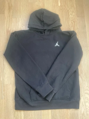 Jordan hoodie - Säljer en svart hoodie från Jordan med den klassiska Jumpman-loggan broderad i vitt på bröstet. Hood Exklusiv design med känguruficka framtill och ribbiga lifter-i-muddar. Perfekt för dig som gillar sportig och stilren streetwear.