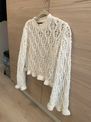Vit stickad tröja (H&M) - Säljer en vit stickad tröja från H&M med virkat vågmönster  Tröjan har rund halsringning är i perfekt längd, långa ärmar och ribbade muddar. Den har knappt används pga den är för liten på mig. Strl : S men fungerar även för XS💞
