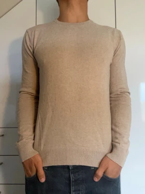 Beige kashmirtröja  - Kashmirtröja från Tiger of Sweden tillverkad i 95% bomull och 5% Kashmir. Strl S. Inga defekter. Modellen är 178 cm och väger 77 kg. Hör gärna av dig vid frågor!