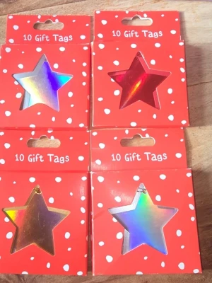 Stjärnformade holografiska presentetiketter  - Säljer fyra paket med stjärnformade presentetiketter i holografiskt papper. Varje paket innehåller 10 etiketter och förpackningen är röd med vita prickar. Stjärnorna har en glansig yta i regnbågsfärger och finns även i rött. Perfekt för att pimpa presenter eller dekorationer. Totalt 4 st förpackningar med 10 i varje